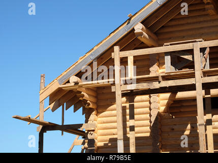 Prozess der Holz- Haus gerade Dachneigung Montage an Wolkenlosen sonnigen Tag Vorderansicht. Holz haus Bau Stockfoto