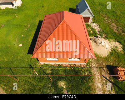 Haus mit einem orangefarbenen Dach aus Metall, Ansicht von oben. Metallische Profil gestrichen Wellpappe auf dem Dach. Stockfoto