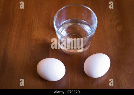 Wasser Glas und zwei Eier auf Tisch Stockfoto