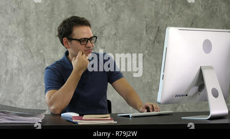 Gelangweilt junger Mann am Schreibtisch vor dem Computer. Stockfoto