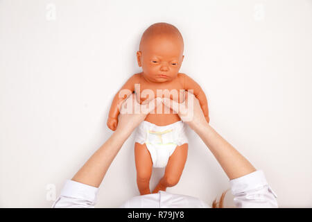 Weibliche Kinderarzt zeigen manuelle Herzdruckmassage Technik auf einer HLW-dummy während Kleinkinder Erste Hilfe Ausbildung. Kardiopulmonale Reanimation praktisch Stockfoto