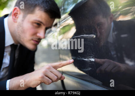 Mann Inspektion beschädigt Auto Stockfoto