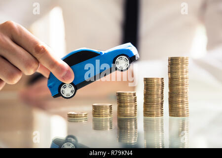 Person mit dem Auto über steigende Gestapelte Münzen Stockfoto