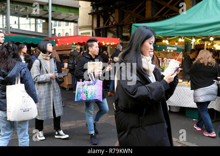 Junge Chinesen, die Touristen essen Essen, Brownies an outdoor Street Food Borough Market in Southwark South London UK KATHY DEWITT Stockfoto