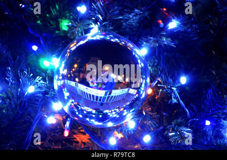 Die Silhouetten der Mann und das Mädchen, das Küssen. Reflexion von ein Paar in Liebe in Ball zum Neuen Jahr auf dem Weihnachtsbaum, die Sitzung des Neuen Stockfoto