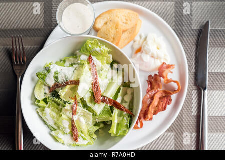 Caesar Salat mit knusprigem Speck und Eier pochieren serviert. Stockfoto