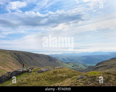 Ein Wanderer steht auf einem cliffedge oberhalb der Honister Pass im Lake District, Cumbria, England. Stockfoto