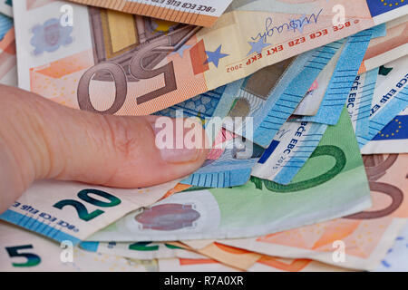 Ein Mann nimmt eine handvoll euro Rechnungen. Stockfoto