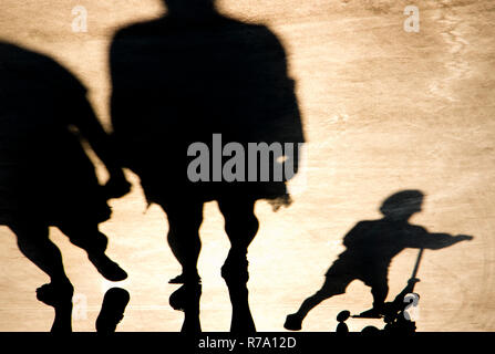 Verschwommene Schatten der Eltern gehen und ein Kind auf einer Push Roller Stockfoto