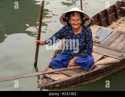 Ältere lächelnde Dame, die vom Flussufer in der antiken Stadt Hoi an, Vietnam, Südostasien auf Fähren wartet Stockfoto