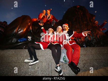 Menschen in Santa Kostüme auf dem Trafalgar Square, London, als sie an Santacon London 2018. Stockfoto