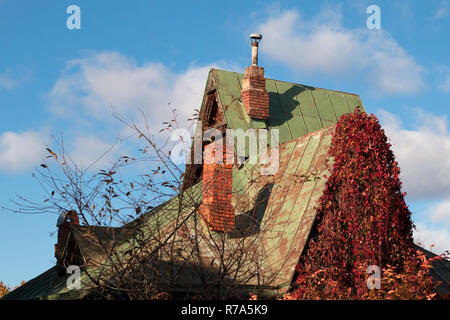 Goblin House mit Schornsteinen und helle rote Blätter von wilden Trauben auf einen Herbst sonniger Tag Stockfoto