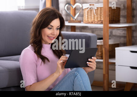 Glückliche junge Frau mit digitalen Tablette zu Hause Stockfoto