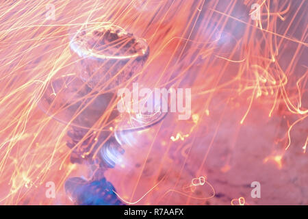 Metallständer, Schüssel mit Shisha mit Folie und Kohlen. Funken des Feuers auf dem Hintergrund. Stockfoto