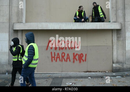 Paris, Frankreich. 8. Dezember 2018. die Demonstranten gehen vor einer roten Schrift lesen 'Macron Harakiri" während einer gelb (gilets jaunes) Protest gegen die Lebenshaltungskosten und die steigenden Ölpreise Credit: Piero Cruciatti/Alamy leben Nachrichten Stockfoto