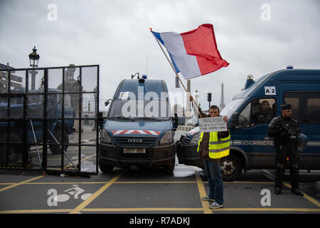 Paris, Frankreich, 8. Dezember, 2018. Demonstrant mit einem Schild und eine Flagge vor einer Straßensperre der Polizei verhindert, dass Menschen zum Place de la Concorde und der rue de Rivoli, Paris ein. Rund 10.000 Demonstranten in gelben Westen in Paris für das vierte Wochenende in einer Reihe demonstrierten gegen Steuern auf Kraftstoff und Rückgang der Kaufkraft zu protestieren, einige fordern Rücktritt des französischen Präsidenten Emmanuel Längestrich. Credit: Christelle Chanut/Alamy leben Nachrichten Stockfoto