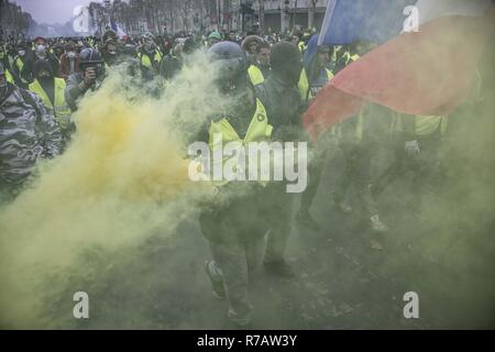 Paris, Frankreich. 8 Dez, 2018. Demonstrant mit gelben Flare und der französischen Flagge im Champs-élysées in der Nähe von Arc De Triomphe während die gelbe Weste Demonstration. Vierte Wochenende im Gelben Westen anti Proteste in Paris, mit Tausenden von Demonstranten vandalizing Autos, Geschäfte oder öffentliche Eigenschaft, Einrichten von Straßensperren um Champs Elysees und Arc De Triomphe. Polizei verwendet, Tränengas und über tausend Verhaftungen. Credit: Georgios Papadopoulos/SOPA Images/ZUMA Draht/Alamy leben Nachrichten Stockfoto