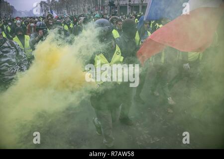 Paris, Frankreich. 8. Dez 2018. Demonstrant mit gelben Flare und der französischen Flagge im Champs-élysées in der Nähe von Arc De Triomphe während die gelbe Weste Demonstration. Vierte Wochenende im Gelben Westen anti Proteste in Paris, mit Tausenden von Demonstranten vandalizing Autos, Geschäfte oder öffentliche Eigenschaft, Einrichten von Straßensperren um Champs Elysees und Arc De Triomphe. Polizei verwendet, Tränengas und über tausend Verhaftungen. Credit: SOPA Images Limited/Alamy leben Nachrichten Stockfoto