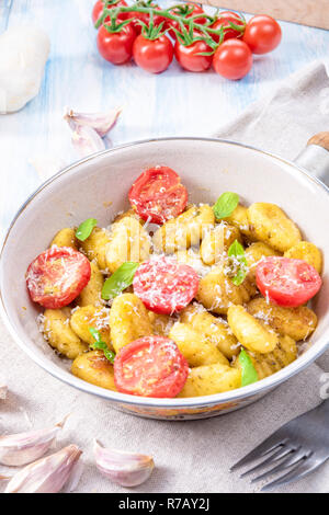 Gnocchi gebacken mit grünem Pesto, Kirschtomaten und Parmesan Stockfoto