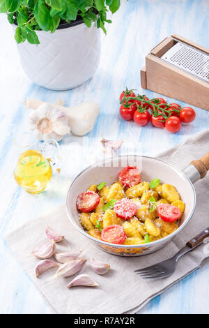 Gnocchi gebacken mit grünem Pesto, Kirschtomaten und Parmesan Stockfoto