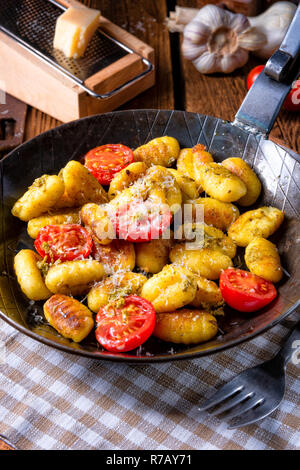 Gnocchi gebacken mit grünem Pesto, Kirschtomaten und Parmesan Stockfoto