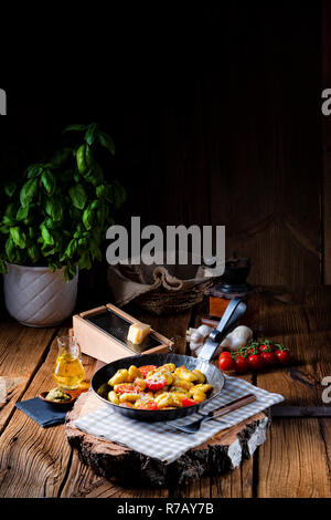 Gnocchi gebacken mit grünem Pesto, Kirschtomaten und Parmesan Stockfoto