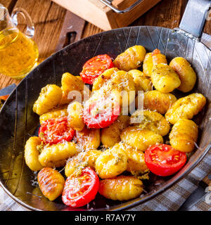 Gnocchi gebacken mit grünem Pesto, Kirschtomaten und Parmesan Stockfoto