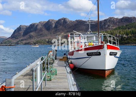 Touristische Yacht "Sula Mhor" gebunden an der Anlegestelle am Loch Carron mit weit entfernten Felsen im Hintergrund - plockton Dorf, Hochland, Schottland Stockfoto