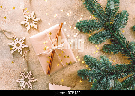 Tanne Zweig, Holzspielzeug und Weihnachten Geschenk Box auf eine beige strukturierten Hintergrund mit den goldenen Sternen Konfetti. Flach, Ansicht von oben Stockfoto