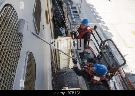 SASEBO, Japan (13. April 2017) Seaman Tylor Spagnola, unten rechts, aus Amsterdam, N.Y., und Seaman Jack Downs, aus Ziegeln, N. J., malen Sie den Rumpf des Amphibious Assault ship USS BONHOMME RICHARD (LHD6). Bonhomme Richard, Vorwärts- und Sasebo, Japan bereitgestellt, das eine schnelle Reaktionsfähigkeit im Falle eines regionalen Kontingenz oder Naturkatastrophe zur Verfügung zu stellen. Stockfoto