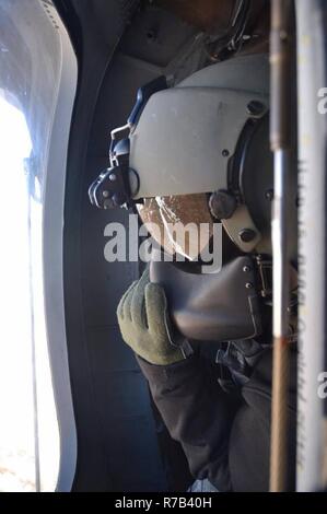 Sgt. Sean Pritchard, ein UH-60 Blackhawk Hubschrauber Mechaniker mit loslösung 2, Golf Company, 2-104 th Allgemeine Unterstützung Aviation Battalion, beobachtet das Gelände während einer Ausbildung Flug in Kodiak, Alaska, im April. Alaska Army National Guard Flieger wurden in Kodiak Arktis Pflege 2017, Multi Service health care Training Unterstützung von Gemeinden in ländlichen Alaska zu unterstützen. Stockfoto