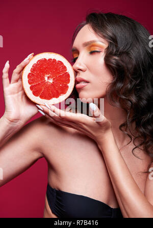 Studio Porträt der schönen jungen Mädchen mit Scheibe Orange (Grapefruit) in den Händen Stockfoto