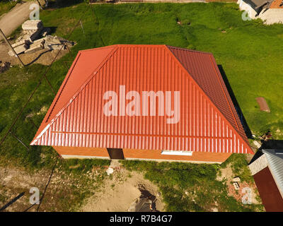 Haus mit einem orangefarbenen Dach aus Metall, Ansicht von oben. Metallische Profil gestrichen Wellpappe auf dem Dach. Stockfoto