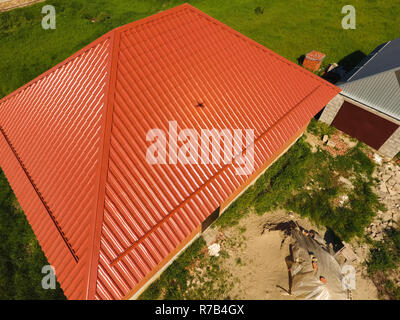 Haus mit einem orangefarbenen Dach aus Metall, Ansicht von oben. Metallische Profil gestrichen Wellpappe auf dem Dach. Stockfoto