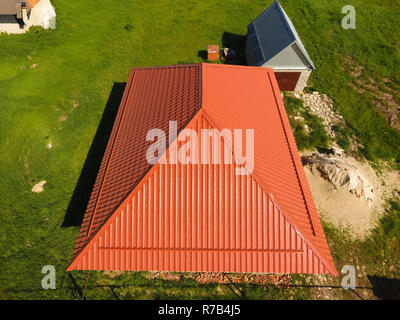 Haus mit einem orangefarbenen Dach aus Metall, Ansicht von oben. Metallische Profil gestrichen Wellpappe auf dem Dach. Stockfoto