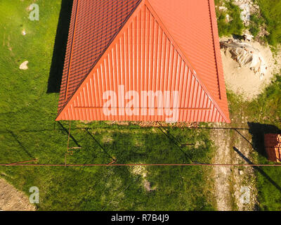 Haus mit einem orangefarbenen Dach aus Metall, Ansicht von oben. Metallische Profil gestrichen Wellpappe auf dem Dach. Stockfoto