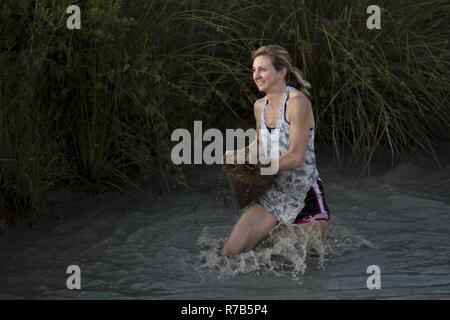 Ein Teilnehmer mit einem Sandsack während durch Wasser treten während der jährlichen Moody Schlamm laufen, 6. Mai 2017, in Ray City, Ga. Der vierte Jahresbericht Moody Schlamm von Erwachsenen und Kind Kurs, der mehr als 600 Teilnehmer mit Hindernissen über 4,2 Meilen Herausforderung bestand. Stockfoto