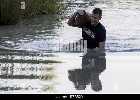 Moody's Schlamm laufen Teilnehmer trägt einen Sandsack durch mehrere Fuß tief im Wasser, 6. Mai 2017, in Ray City, Ga. Der vierte Jahresbericht Moody Schlamm von Erwachsenen und Kind Kurs, der mehr als 600 Teilnehmer mit Hindernissen über 4,2 Meilen Herausforderung bestand. Stockfoto