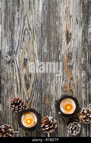 Brennende Kerzen und -kegel auf einem alten Holztisch. Stockfoto