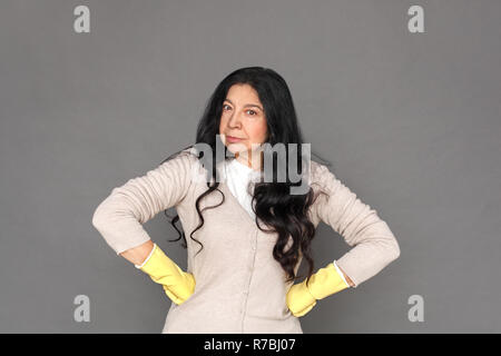 Freestyle. Reife lady in Gummihandschuhe auf grau Hände isoliert stehen auf den Hüften schwere Stockfoto