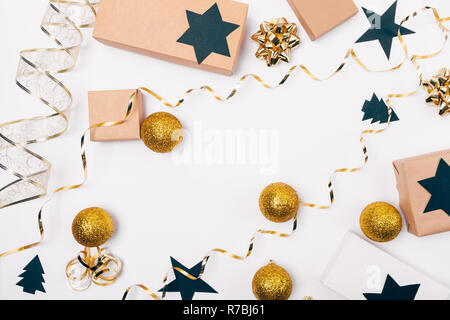 Festliche flach Zusammensetzung der Verpackung Weihnachtsgeschenke mit den goldenen Bögen, Kartons, Papier - schwarze Sterne ausschneiden und Pinien auf weiße Tabelle, Ansicht von oben. Stockfoto