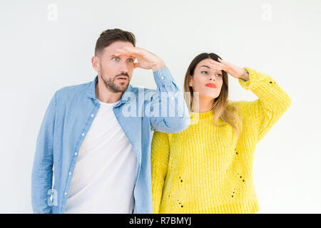 Junge schöne Paar togheter über isolierte Hintergrund sehr glücklich und lächelnd weit entfernt, mit der Hand über den Kopf. Suche Konzept. Stockfoto