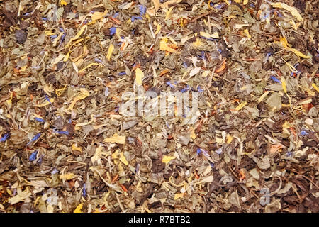Tee Schwarz langen Blatt mit Himbeere Beeren, Blätter von Blackberry und eine blaue Kornblume auf einem Zähler im Markt einen Hintergrund Kaffee Stockfoto