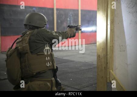 Dozenten mit Ausbildung Co., US Marine Corps Security Force Regiment zu prüfen, um ihre Studenten mit taktischen Bewertungen L-förmige Zimmer während der Close Quarters Battle 2-17 Kurs klar 10. Mai an Bord Naval Support Activity Nordwesten Anhang, Chesapeake, Virginia. Studenten auf ihre Fähigkeit, ein Zimmer zu löschen geprüft wurden und wie schnell Sie in der Lage sind, mögliche Bedrohungen und die Insassen zu adressieren. Stockfoto