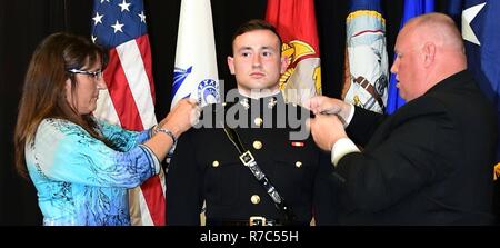 MADISON, Wisconsin, USA, (Mai 13. 2017) – Universität von Wisconsin-Madison Naval Reserve Officers Training Corps (NROTC) Midshipman 1. Klasse Cogan Kirchenwitz, 22, aus Pardeeville, Wisconsin, hat seine U. S. Marine Corps 2. Leutnant gold Bars auf von seiner Mutter Lori festgesteckt und Vater im Ruhestand Marine Corps Gunnery SGT Patrick Kirchenwitz während einer ROTC Joint Service Officer Inbetriebnahme Zeremonie im Concerto Zimmer des Gordon Dining & Event Center auf dem Campus , Mai 13. Die neun Navy und Marine Corps Midshipmen, 10 Armee und 16 Luftwaffe jüngstere Söhne wurden beauftragt, nach dem Studium Beginn ceremonie Stockfoto