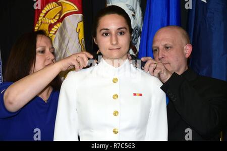 MADISON, Wisconsin, USA, (Mai 13. 2017) – Universität von Wisconsin-Madison Naval Reserve Officers Training Corps (NROTC) Midshipman 1. Klasse Dominique Bowers, 22, aus Sturgeon Bay, Wisconsin, hat ihr U. S. Navy Ensign Schulterklappen angeheftet auf von ihrer Mutter Bridget und Vater Jim Bowers während einer ROTC Joint Service Officer Inbetriebnahme Zeremonie im Concerto Zimmer des Gordon Dining & Event Center auf dem Campus , Mai 13. Die neun Navy und Marine Corps Midshipmen, 10 Armee und 16 Luftwaffe jüngstere Söhne wurden beauftragt, nach Beginn der Abschlussfeiern an der Universität Camp Randall Fußball S statt Stockfoto