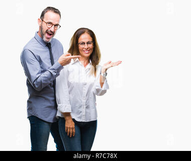 Mittleres Alter spanischer verliebtes Paar Brillen über isolierte Hintergrund erstaunt und lächelt in die Kamera während der Präsentation und mit der Hand nach w Stockfoto
