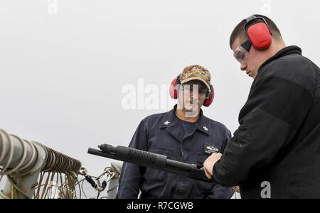 WESTERN PACIFIC (12. Mai 2017) Der Gunner Mate 1. Klasse Joseph Alvarez (links), aus San Diego, fungiert als eine Reihe Supervisor als Elektroniker 2. Klasse Miguel Hernandez, von Dichtmasse, New York, lasten Munition in einem Mossberg 500 Schrotflinte während der Einarbeitung live-Fire Schießen an Bord der Arleigh-Burke-Klasse geführte Anti-raketen-Zerstörer USS Wayne E.Meyer (DDG108) Die US-Marine die Indo-Asia Pacific routinemäßig Seit mehr als 70 Jahren die Förderung von Frieden und Sicherheit in der Region bewacht hat. Stockfoto