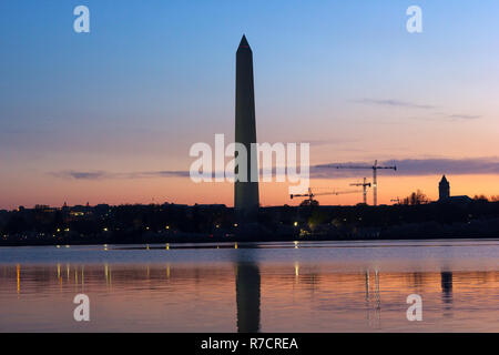 Washington Monument in der Dämmerung mit Skyline im Hintergrund. Bunte Reflexionen in Tidal Basin Gewässern. Stockfoto