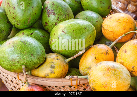 Avocado und gelbe Passionsfrucht in einem Korb an einer traditionellen Bauernmarkt, Bali, Indonesien. Stockfoto